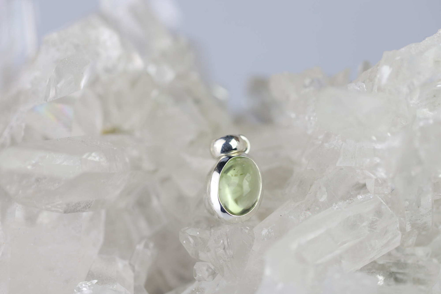 Kristallwerk präsentiert: Anhänger geschliffener Peridot Cabochon in Silber 925 gefasst auf einer Bergkristall Stufe.