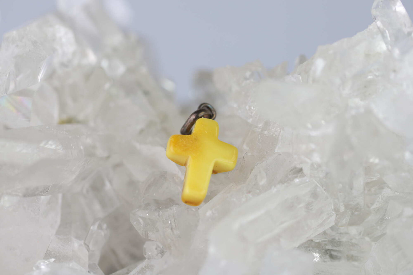 Kristallwerk präsentiert: Anhänger gelbgoldenes Bernstein Kreuz mit Silberöse auf einer Bergkristall Stufe.