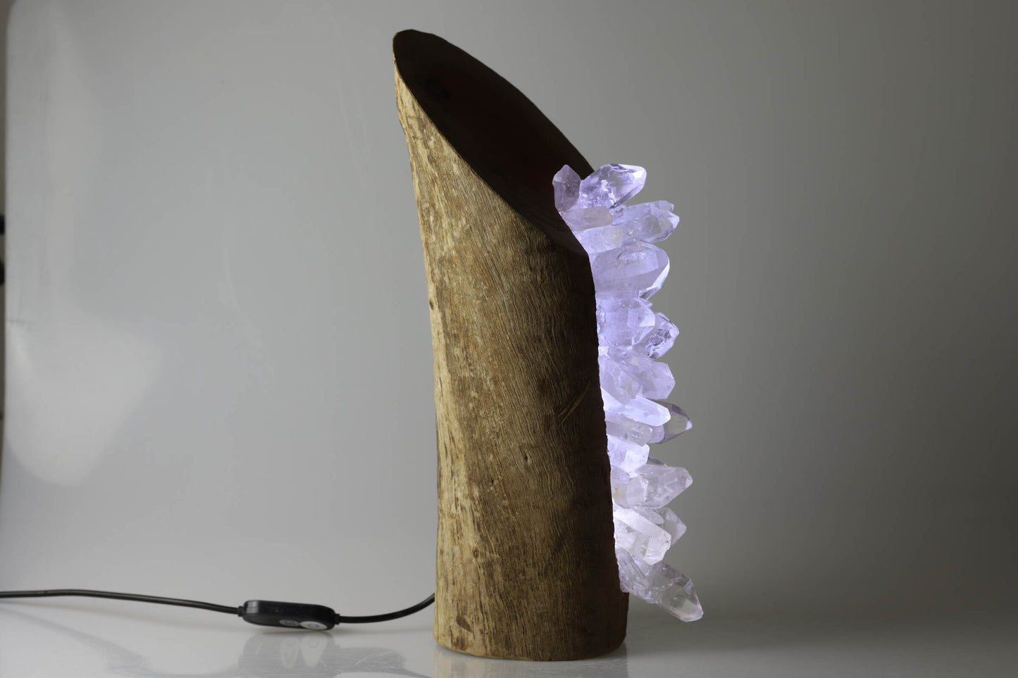 Kristallwerk präsentiert eine LED Lampe bestehend aus einem Holzstrunk bestückt mit rohen und klaren Bergkristallen.