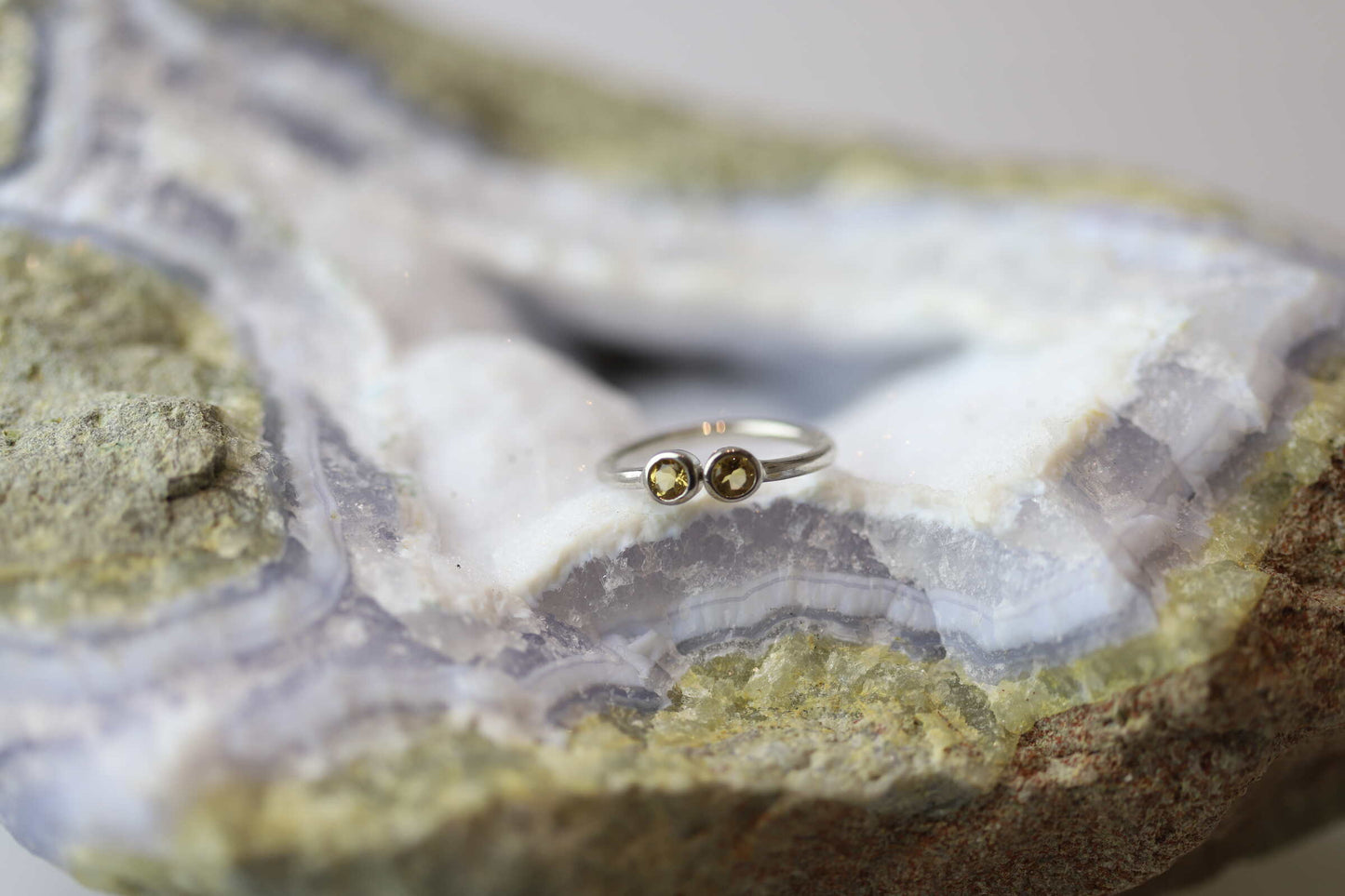 Kristallwerk präsentiert einen Ring aus Silber 925 mit zwei facettierten goldgelben Citrinen auf einer Chalcedongeode.