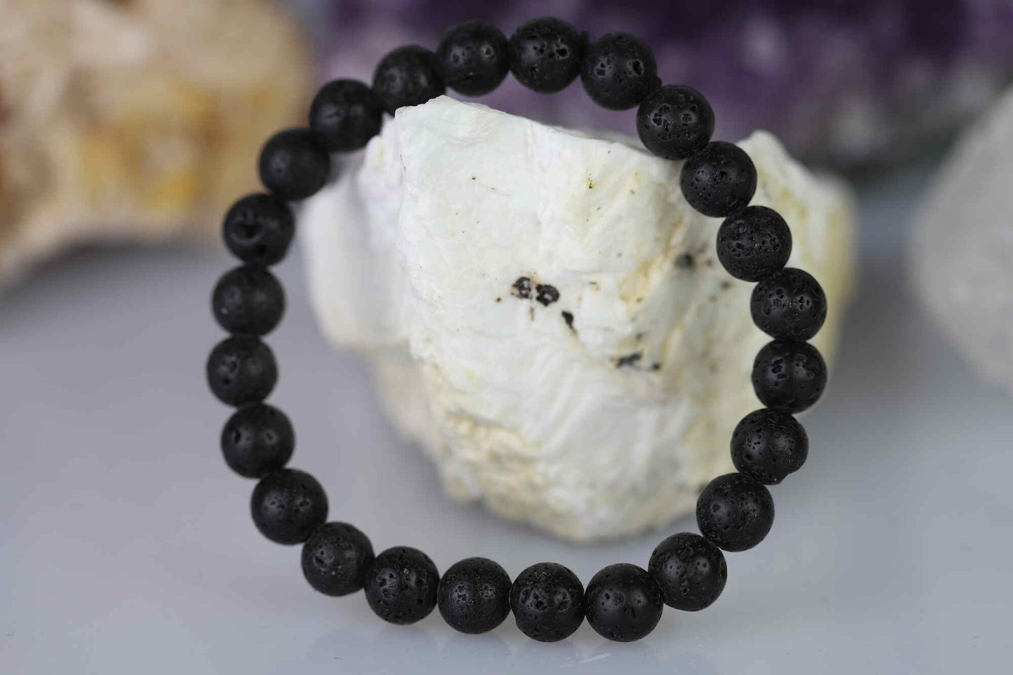 Kristallwerk präsentiert: Armband aus matten Lava-Stein Kugeln angelehnt an einem Barytstein.