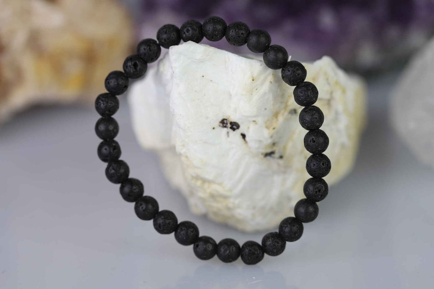 Kristallwerk präsentiert: Armband aus matten Lava-Stein Kugeln angelehnt an einem Barytstein.