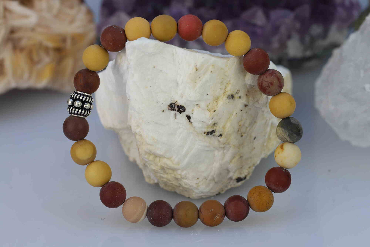 Kristallwerk präsentiert: Armband aus farbenfrohen und matten Mookait Kugeln mit einem zusätzlichen Metallzwischenstück auf einem Barytstein.