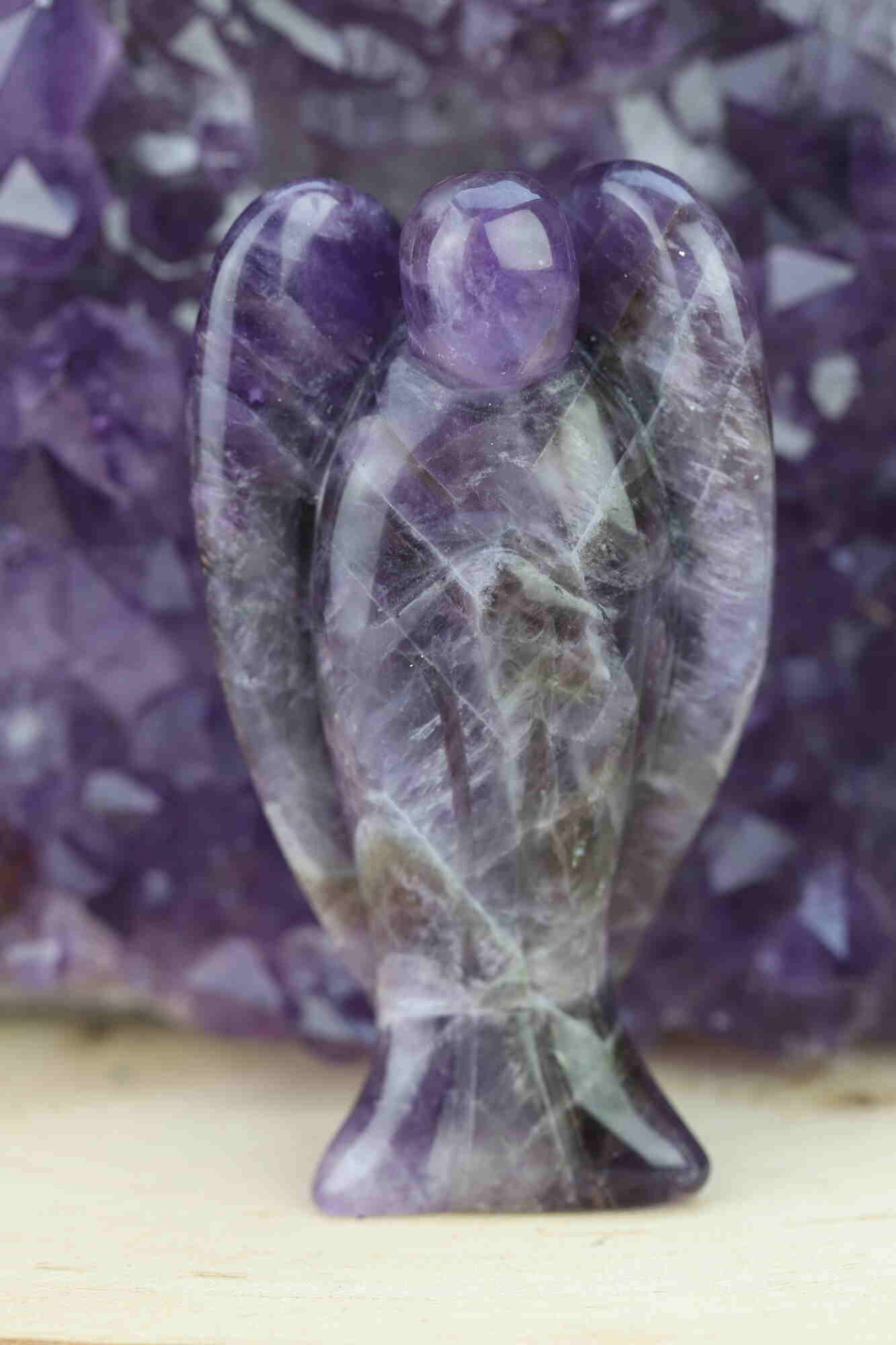 Kristallwerk präsentiert: Engel aus Amethyst vor unscharfer Amethyststufe .