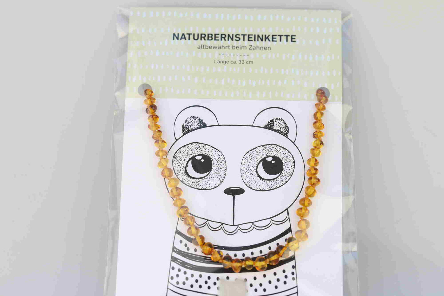 Kristallwerk präsentiert: Bernsteinkette für Bäbys auf einer Geschenkskarte eingepackt und mit einem Tierdesign versehen.