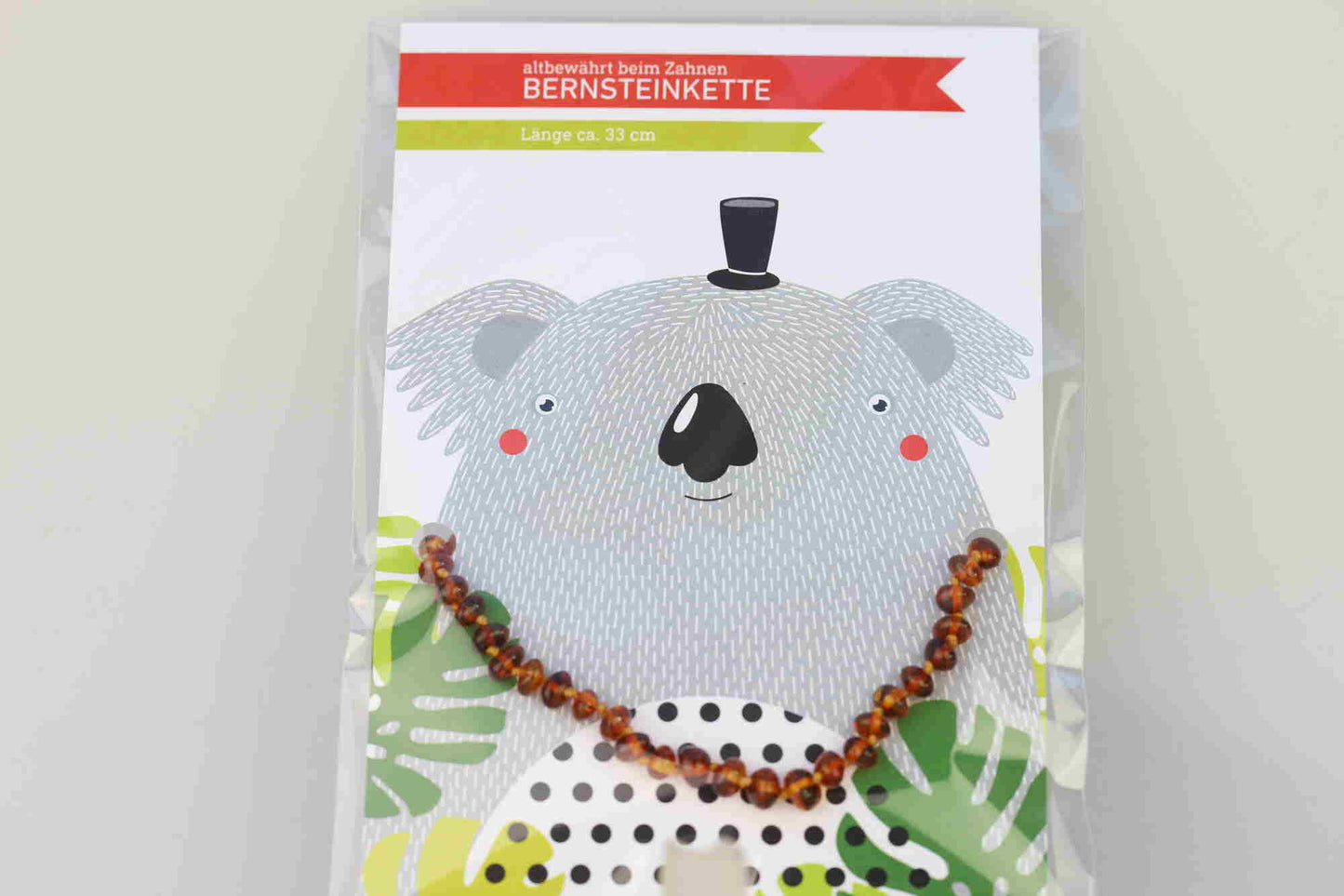 Kristallwerk präsentiert: Bernsteinkette für Bäbys auf einer Geschenkskarte eingepackt und mit einem Tierdesign versehen.