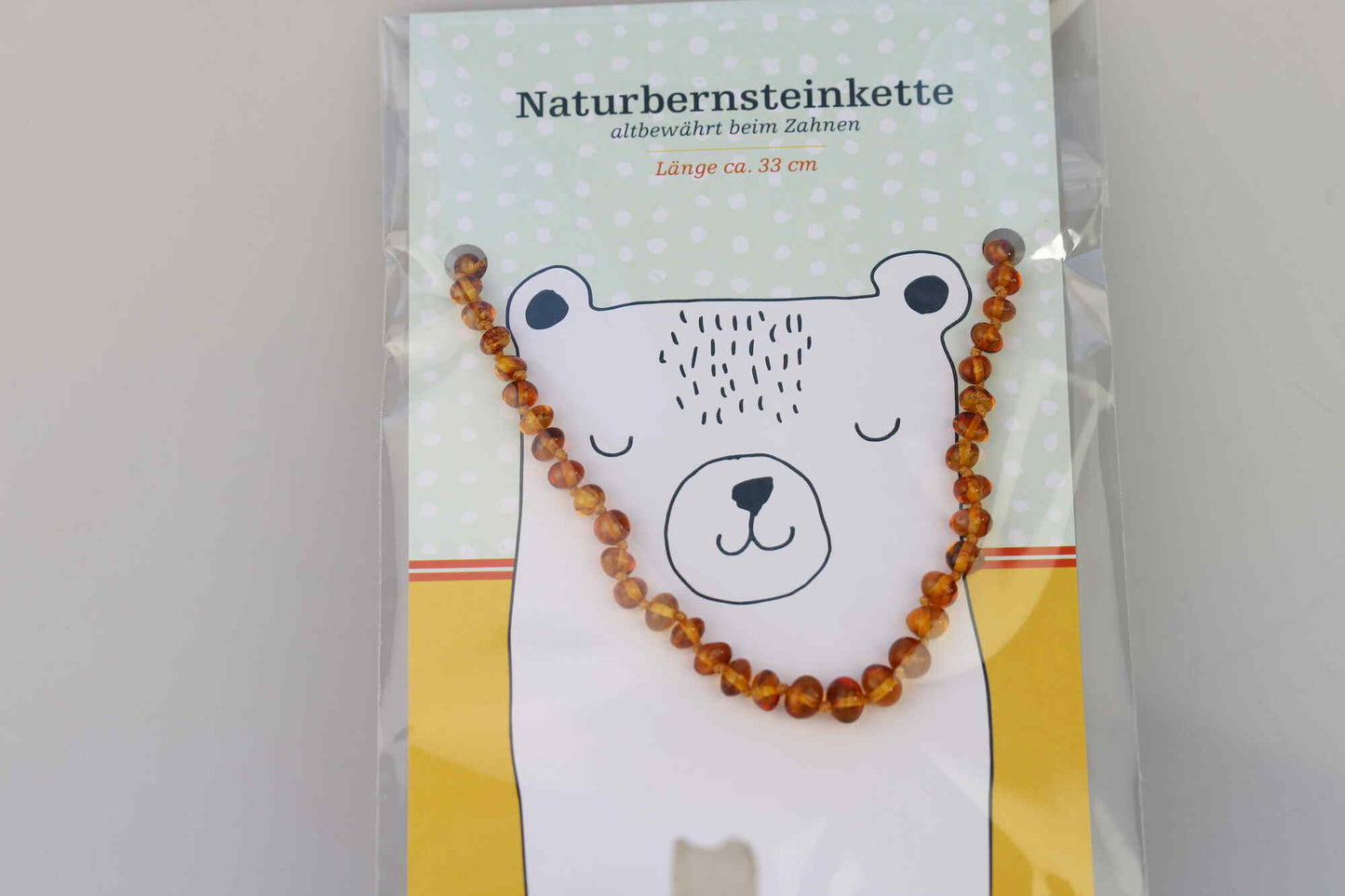 Kristallwerk präsentiert: Bernsteinkette für Bäbys auf einer Geschenkskarte eingepackt und mit einem Tierdesign versehen.