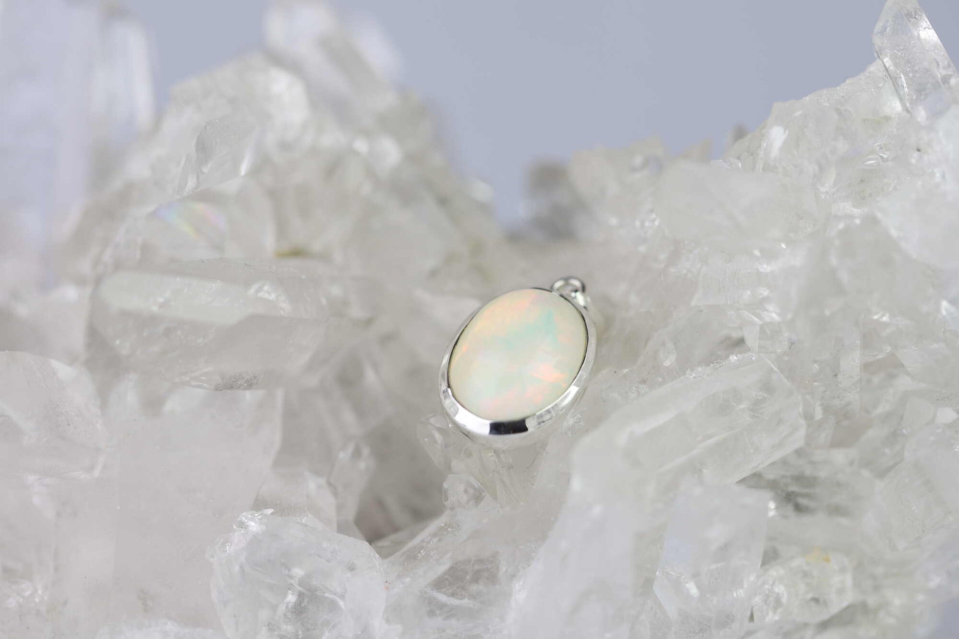 Kristallwerk präsentiert: Anhänger irisierender Opal Cabochon in Silber 925 gefasst auf einer Bergkristall Stufe.