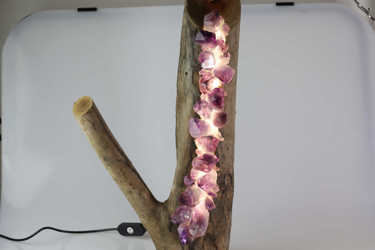 Kristallwerk präsentiert eine LED Lampe bestehend aus einem Holzstrunk bestückt mit rohen und glänzenden Amethysten.