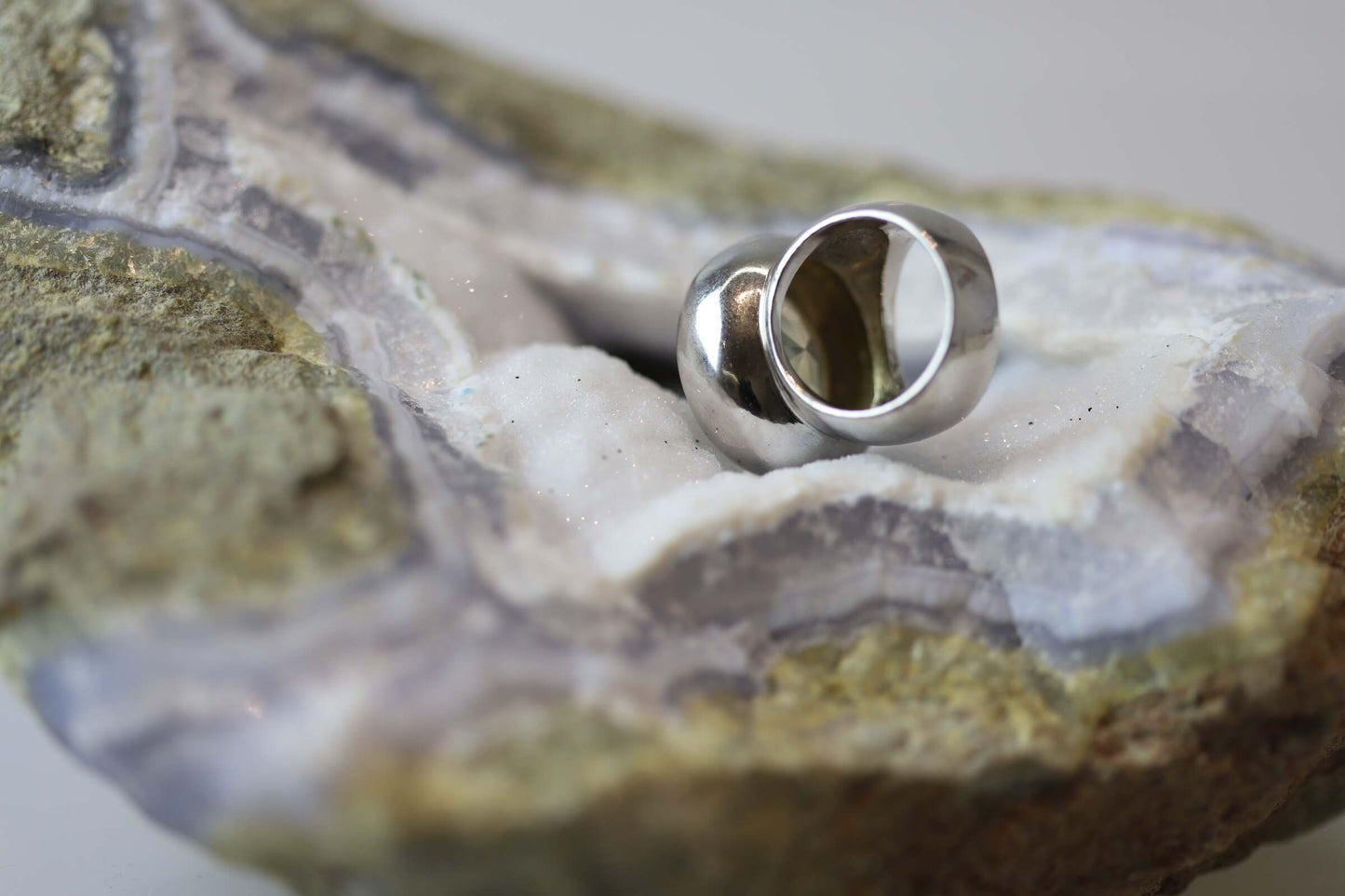 Kristallwerk präsentiert einen leuchtenden facettierten und runden Citrin Ring aus Silber massiv auf einer Chalcedongeode..