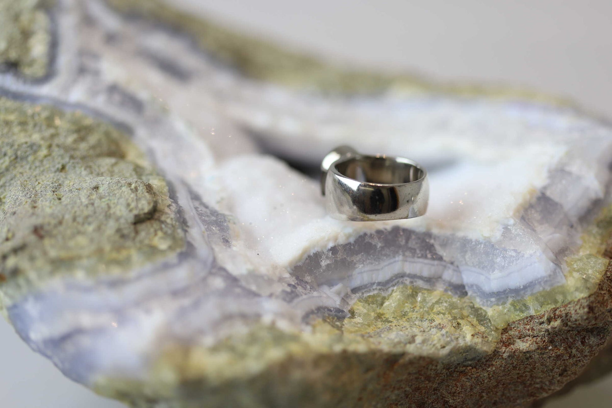 Kristallwerk präsentiert einen leuchtenden facettierten und ovalen Rauchquarz Ring aus Silber massiv auf einer Chalcedongeode..