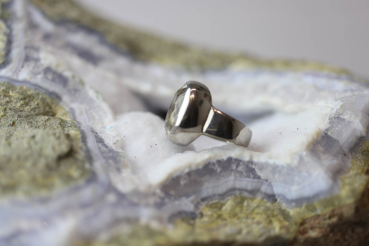 Kristallwerk präsentiert einen Ring aus Silber 925 mit facettiertem und glasklarem Bergkristall auf einer Chalcedongeode.