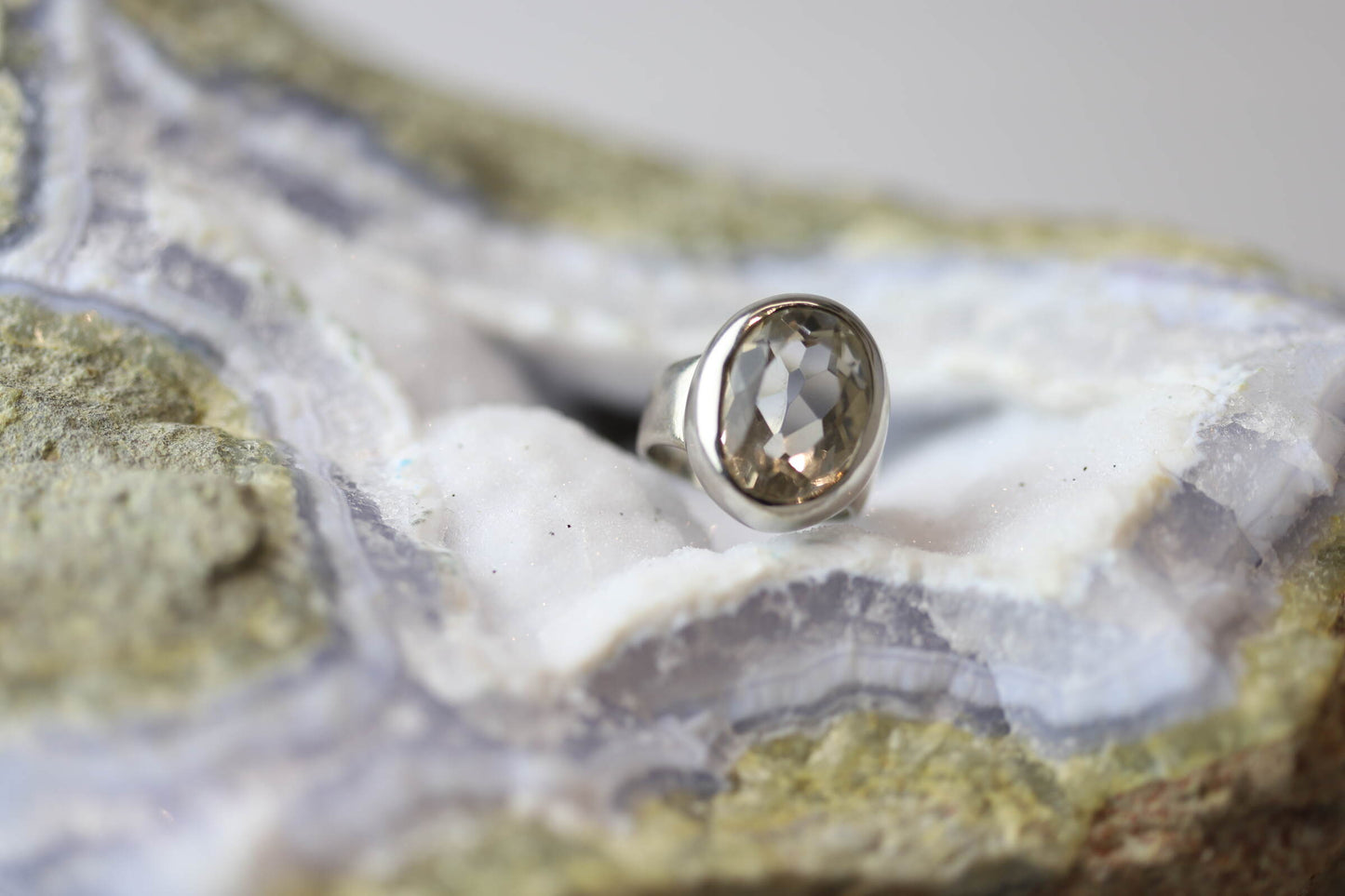 Kristallwerk präsentiert einen Ring aus Silber 925 mit facettiertem und glasklarem Bergkristall auf einer Chalcedongeode.