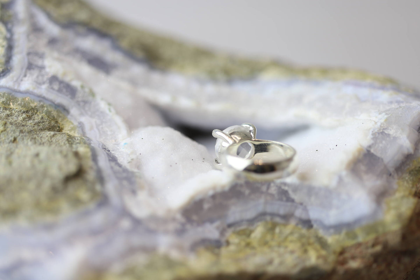 Kristallwerk präsentiert einen Ring aus Silber 925 mit facettiertem und glasklarem Bergkristall auf einer Chalcedongeode.