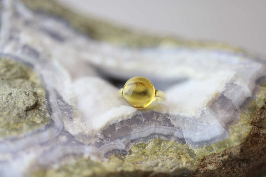 Kristallwerk präsentiert einen Ring aus Gold mit einem goldfarbigen und klaren Citrin  auf einer Chalcedongeode.