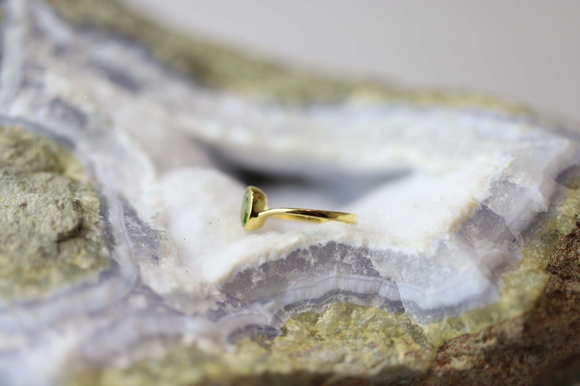 Kristallwerk präsentiert einen Ring aus Silber vergoldet mit einem facettiertem und ovalem Peridot auf einer Chalcedongeode.