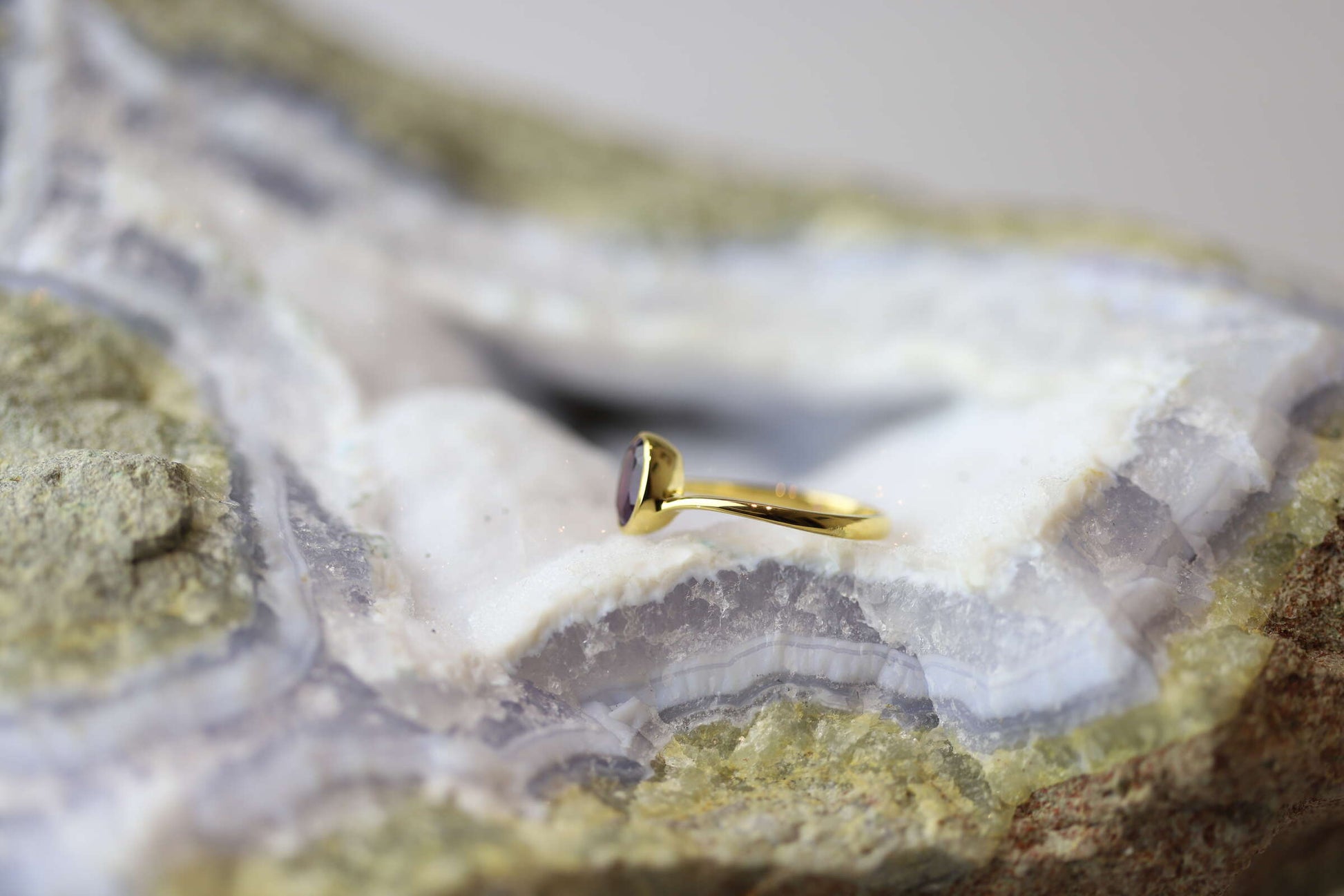 Kristallwerk präsentiert einen Ring aus Silber vergoldet mit einem facettiertem und ovalem Amethyst auf einer Chalcedongeode.