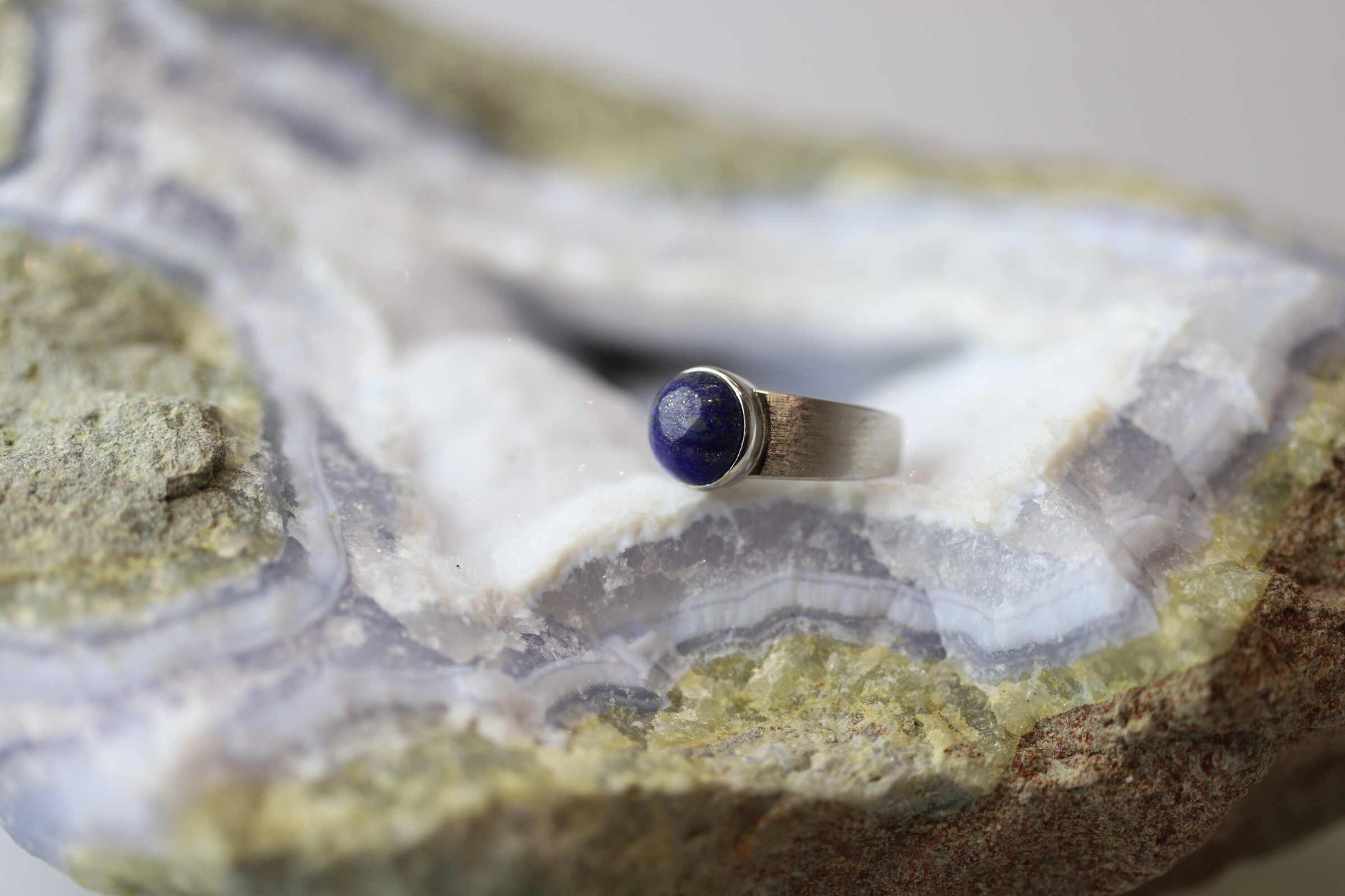 Kristallwerk präsentiert einen Ring aus Silber 925 mit einem polierten Lapislazuli Cabochon auf einer Chalcedongeode.