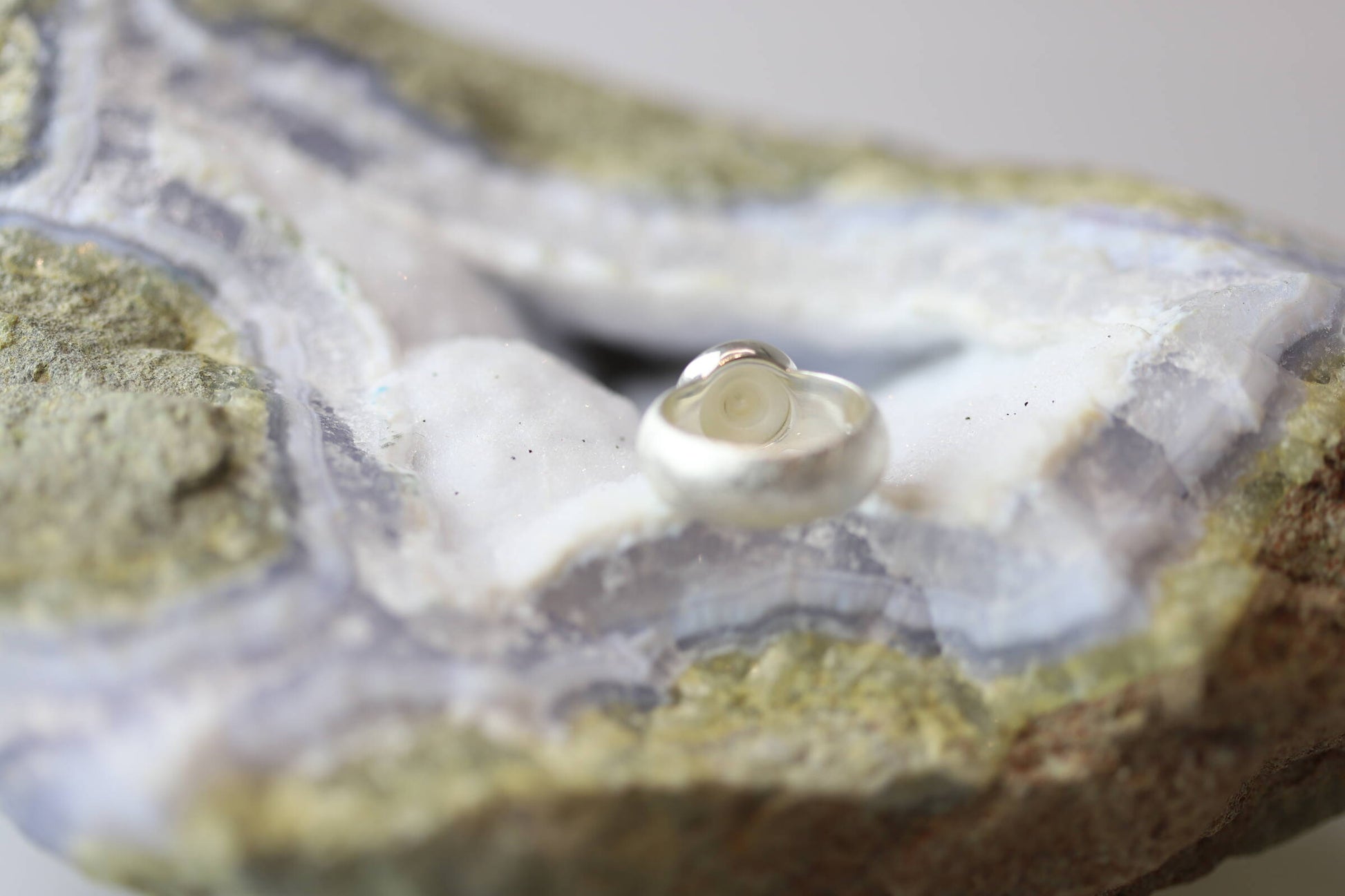 Kristallwerk präsentiert einen Ring aus Silber 925 mit einer polierten und glänzenden Süsswasserperle auf einer Chalcedongeode.