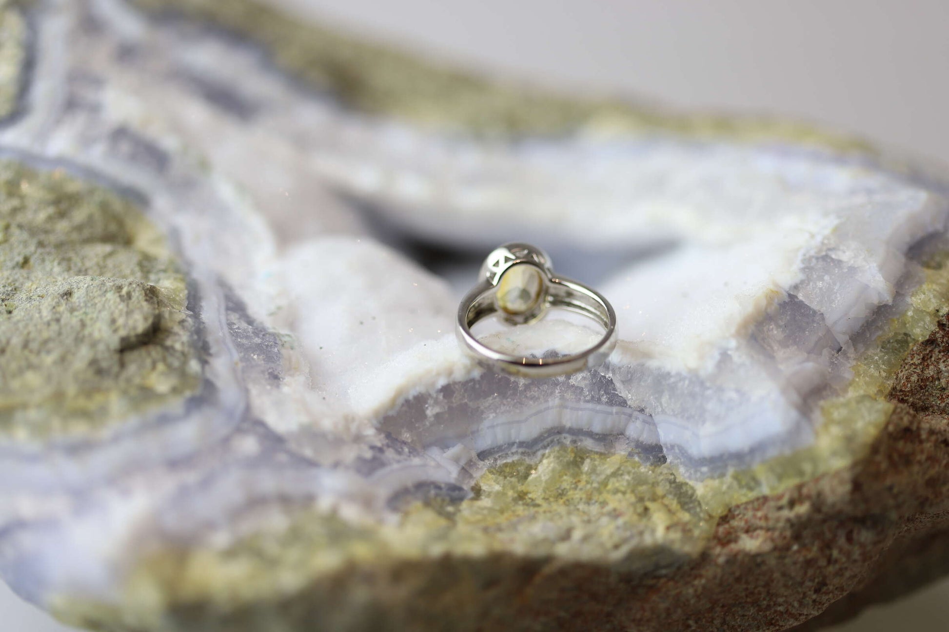 Kristallwerk präsentiert einen Ring aus Silber 925 mit einem facettierten und goldgelben Citrin auf einer Chalcedongeode