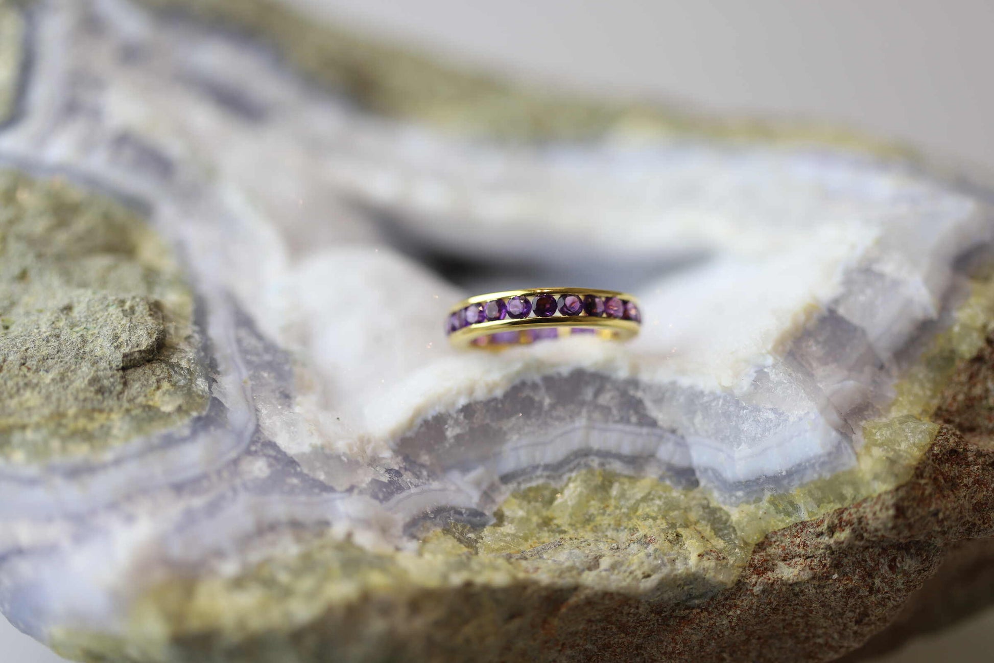 Kristallwerk präsentiert einen Alliance Ring aus Silber vergoldet mit facettierten Amethysten auf einer Chalcedongeode.