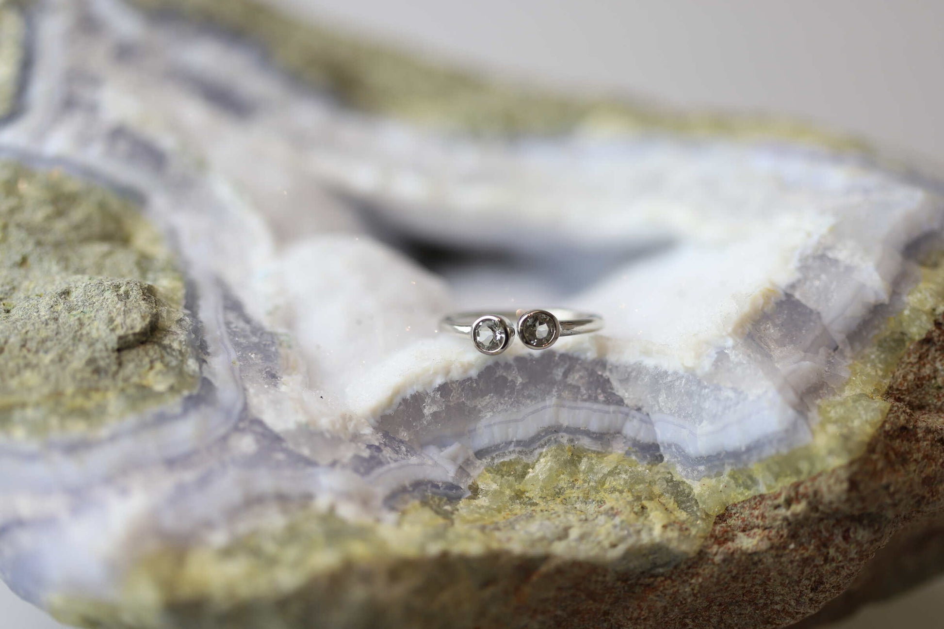 Kristallwerk präsentiert einen Ring aus Silber 925 mit zwei facettierten weissen Edeltopas auf einer Chalcedongeode.