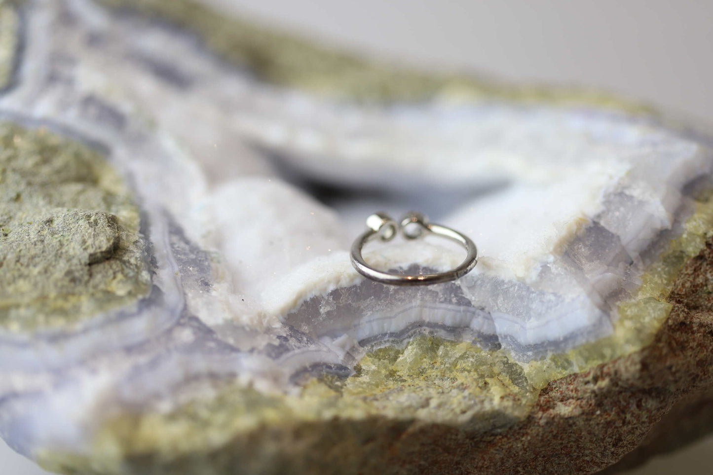 Kristallwerk präsentiert einen Ring aus Silber 925 mit zwei facettierten weissen Edeltopas auf einer Chalcedongeode.