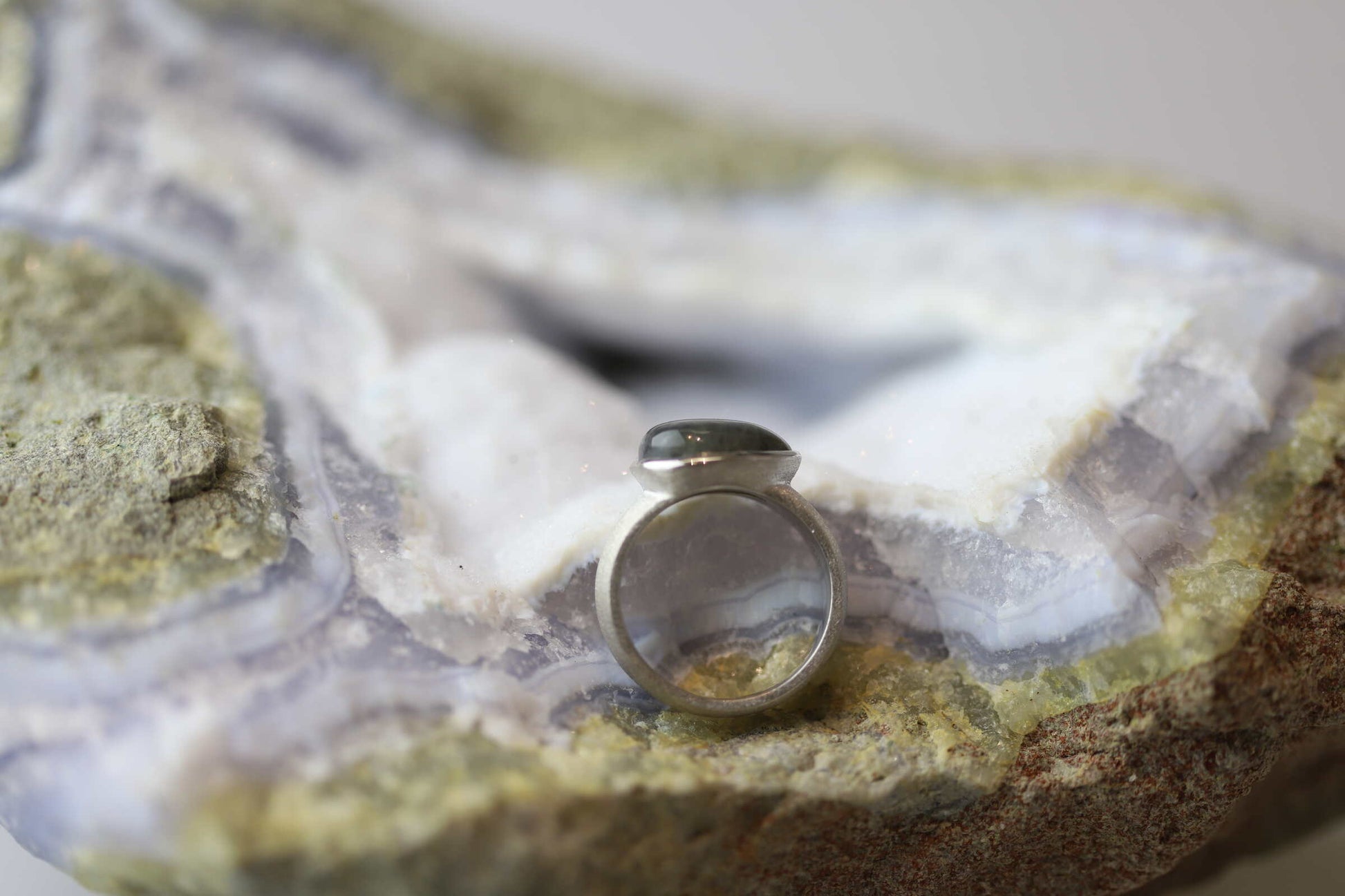 Kristallwerk präsentiert einen Ring aus Silber 925 mit einem polierten und irisierenden Labradorit auf einer Chalcedongeode.