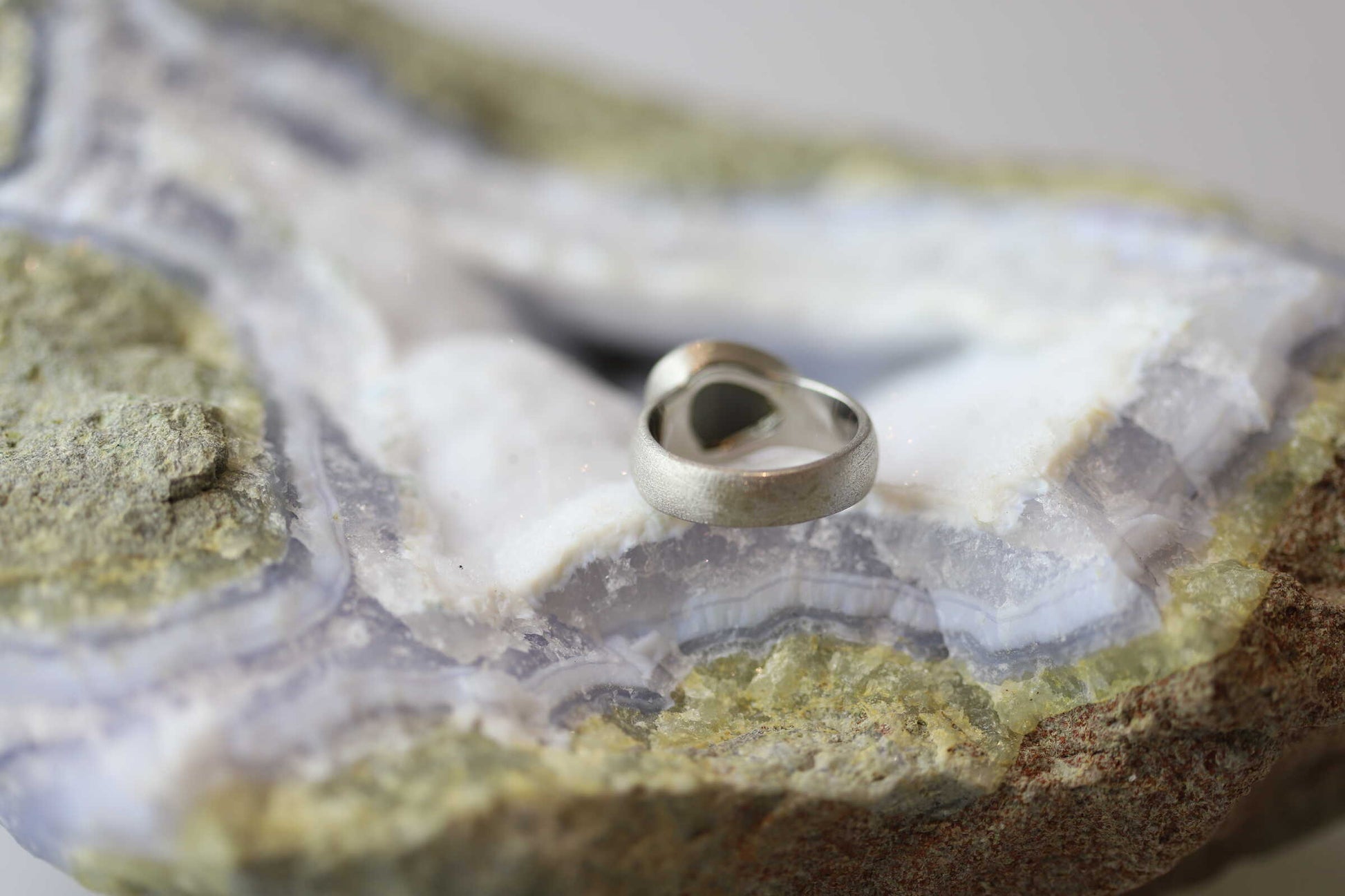 Kristallwerk präsentiert einen Ring aus Silber 925 mit einem polierten und irisierenden Labradorit auf einer Chalcedongeode.