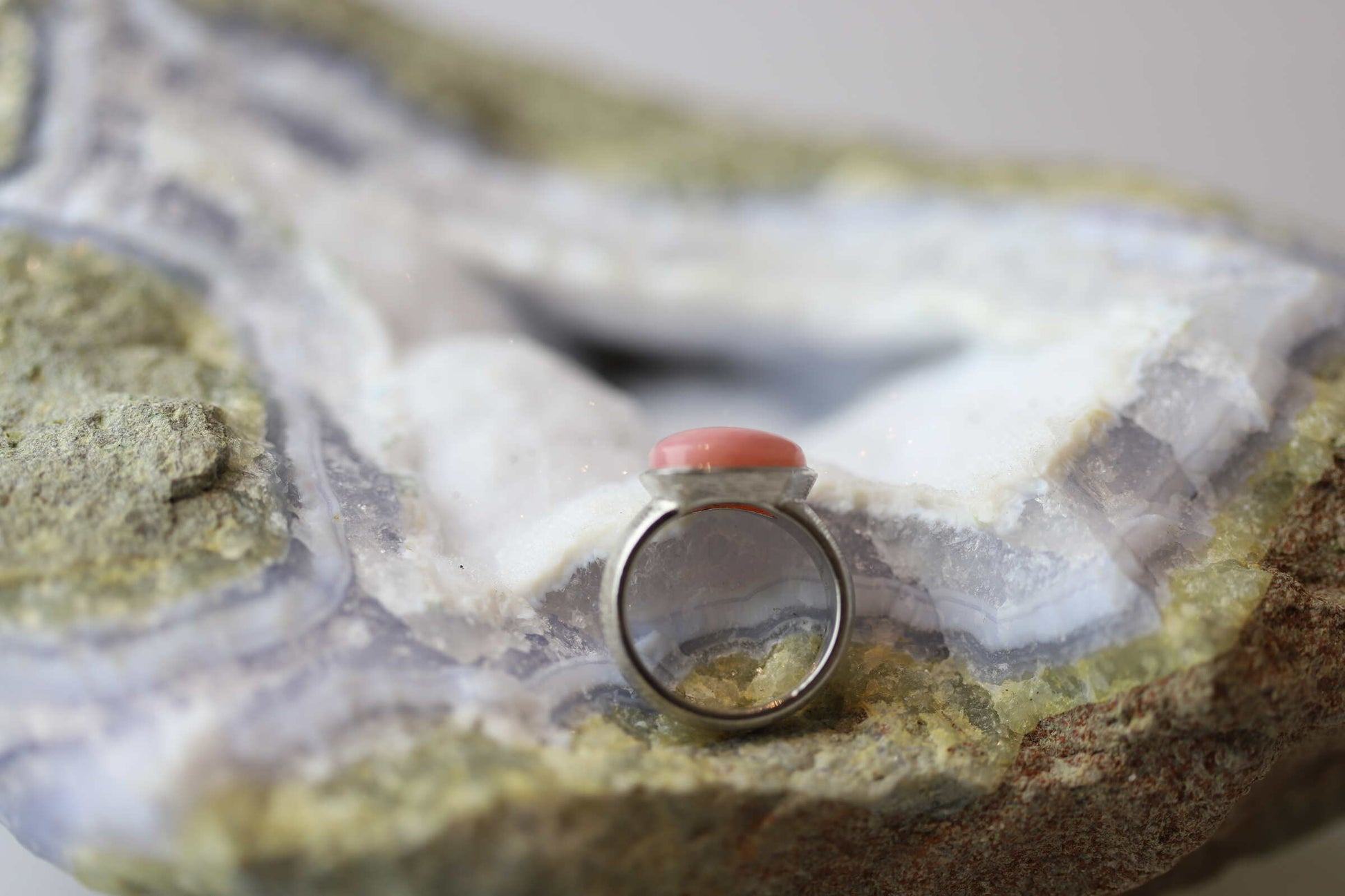 Kristallwerk präsentiert einen Ring aus Silber 925 mit einem polierten und pinken Opal auf einer Chalcedongeode.