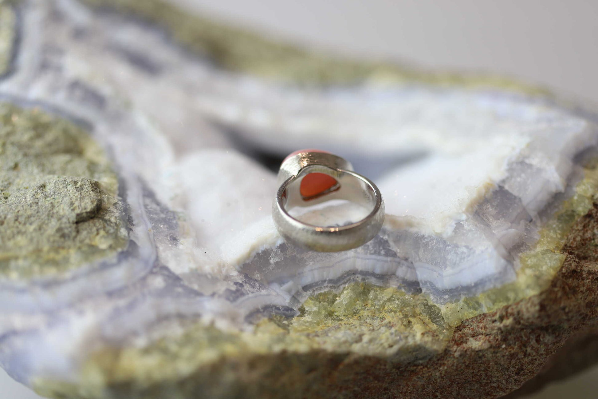 Kristallwerk präsentiert einen Ring aus Silber 925 mit einem polierten und pinken Opal auf einer Chalcedongeode.