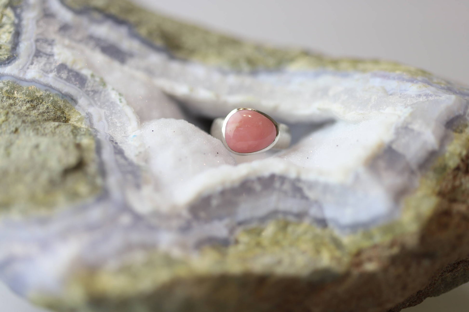 Kristallwerk präsentiert einen Ring aus Silber 925 mit einem polierten und pinken Opal auf einer Chalcedongeode.