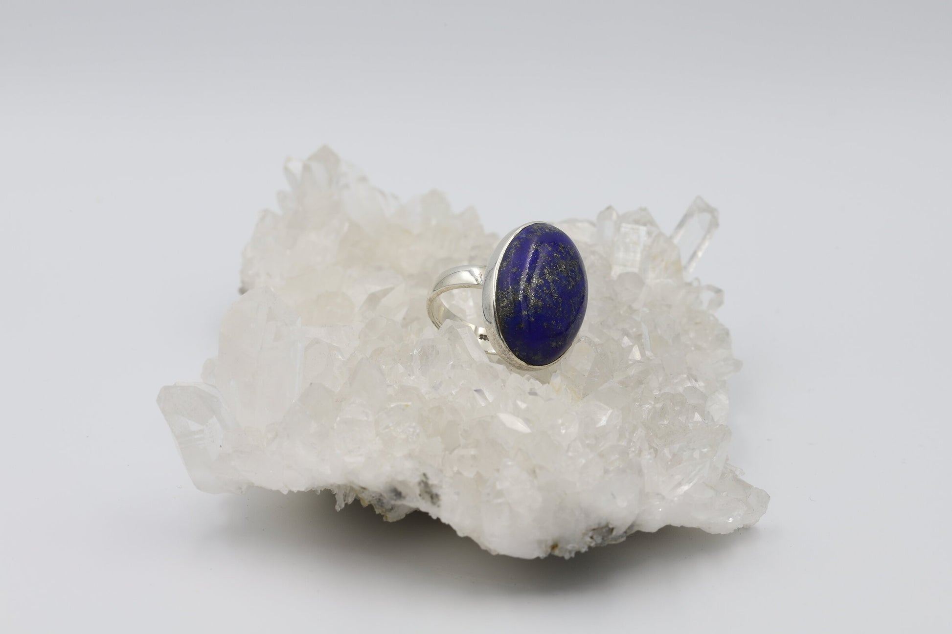 Kristallwerk präsentiert einen Ring aus Silber 925 mit einem polierten Lapislazuli Cabochon auf einer Bergkristallstufe