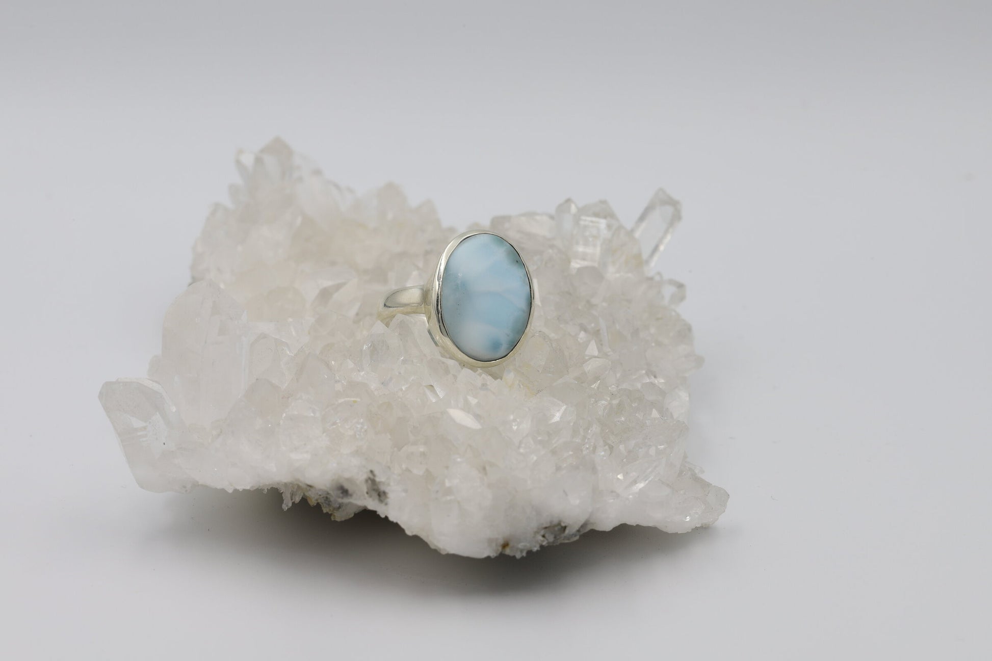 Kristallwerk präsentiert einen Ring aus Silber 925 mit einem polierten Larimar Cabochon auf einer Bergkristallstufe.