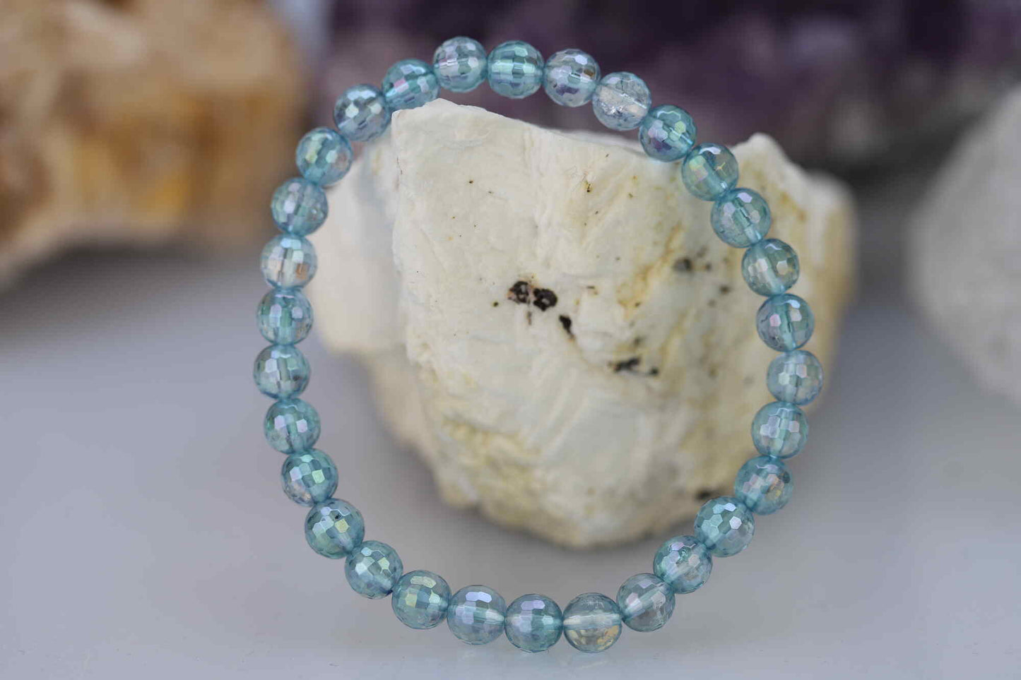 Kristallwerk präsentiert: Armband aus glänzenden und facettierten Aqua Aura Kugeln auf einem weissen Barytstein.