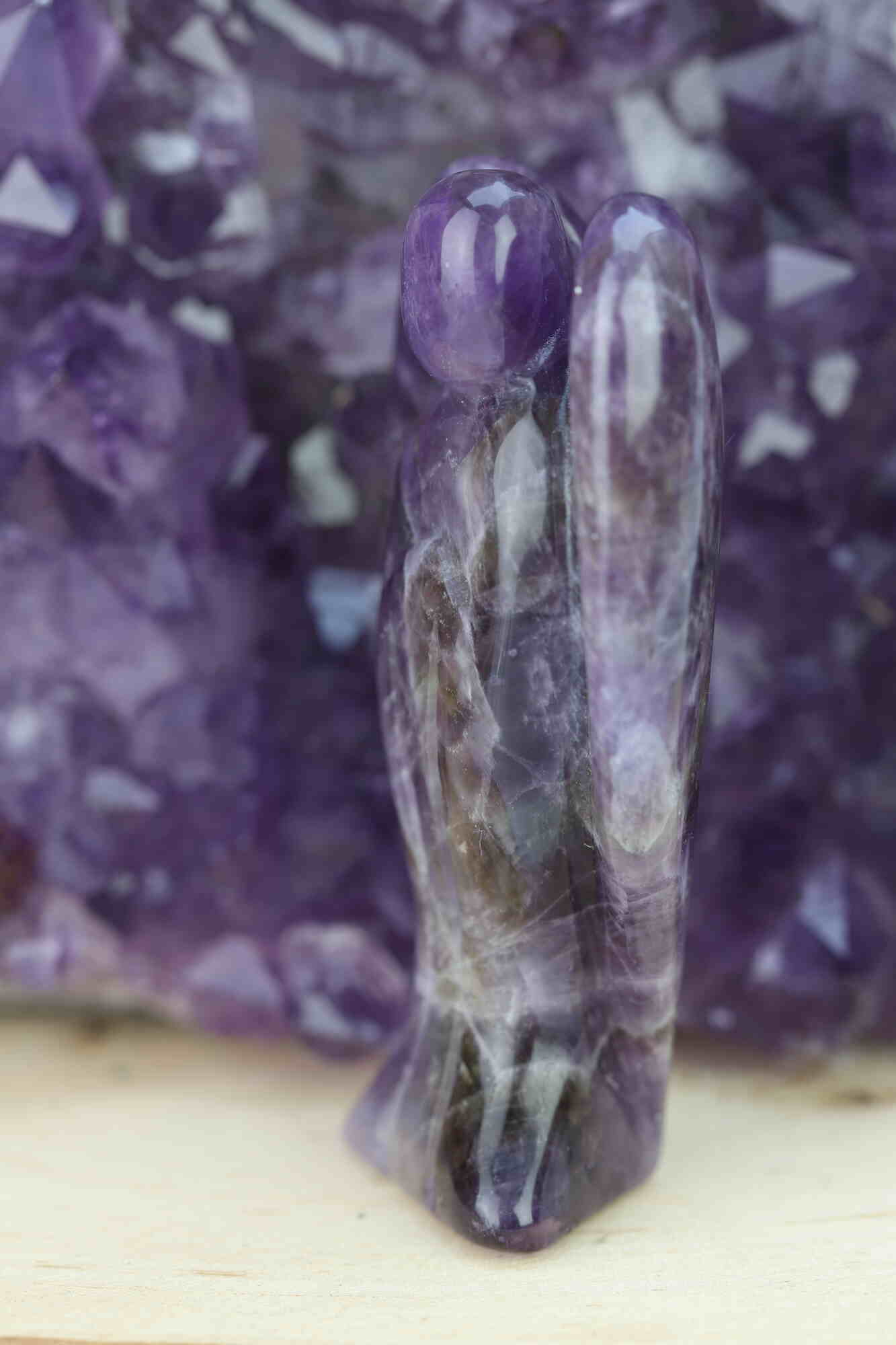 Kristallwerk präsentiert: Engel aus Amethyst vor unscharfer Amethyststufe .