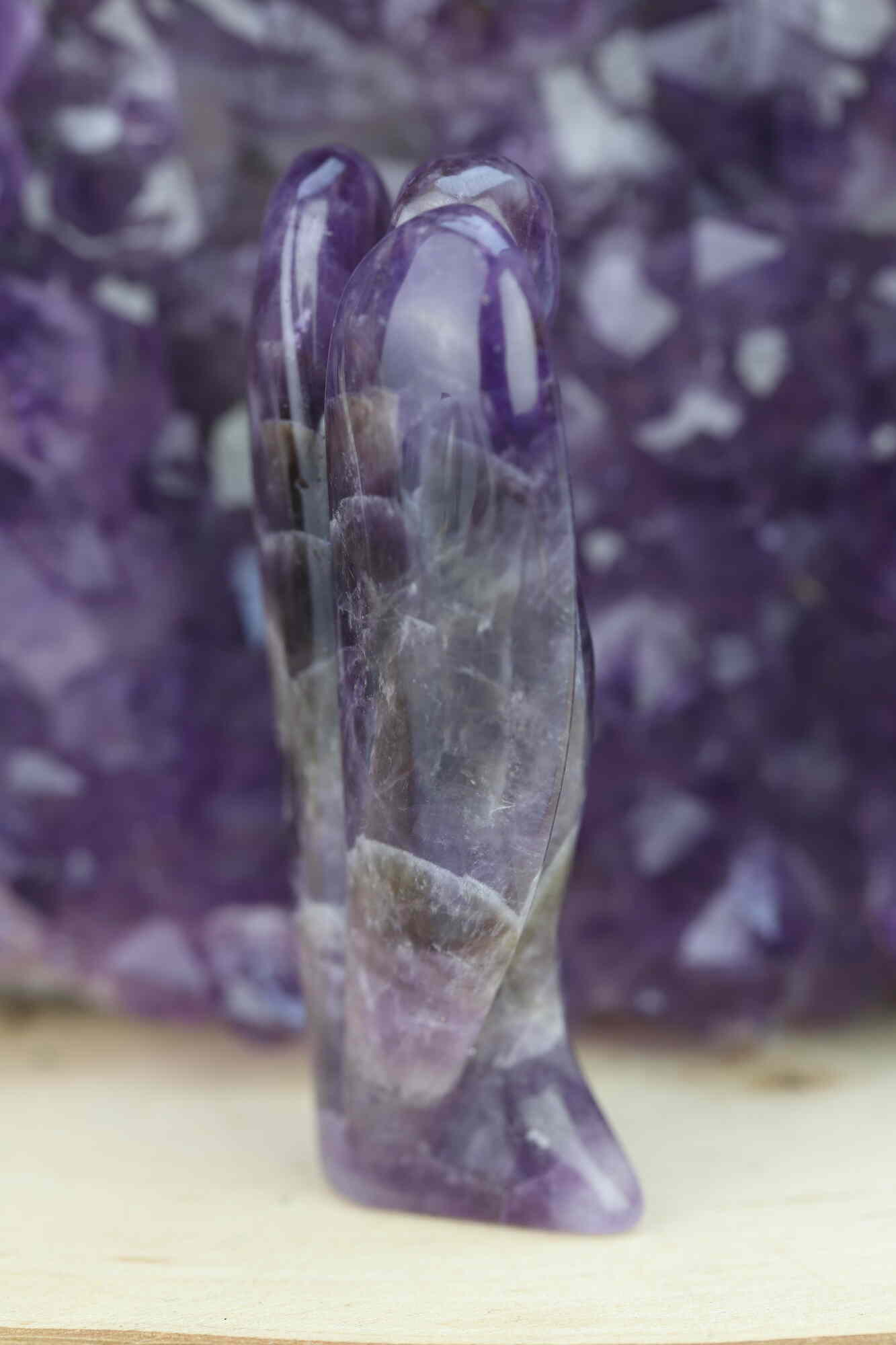 Kristallwerk präsentiert: Engel aus Amethyst vor unscharfer Amethyststufe .