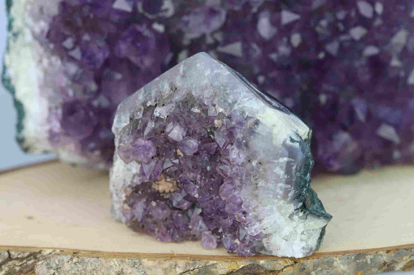 Kristallwerk präsentiert: Rohe Schätze Amethyst Spitze vor unscharfer Amethyststufe.