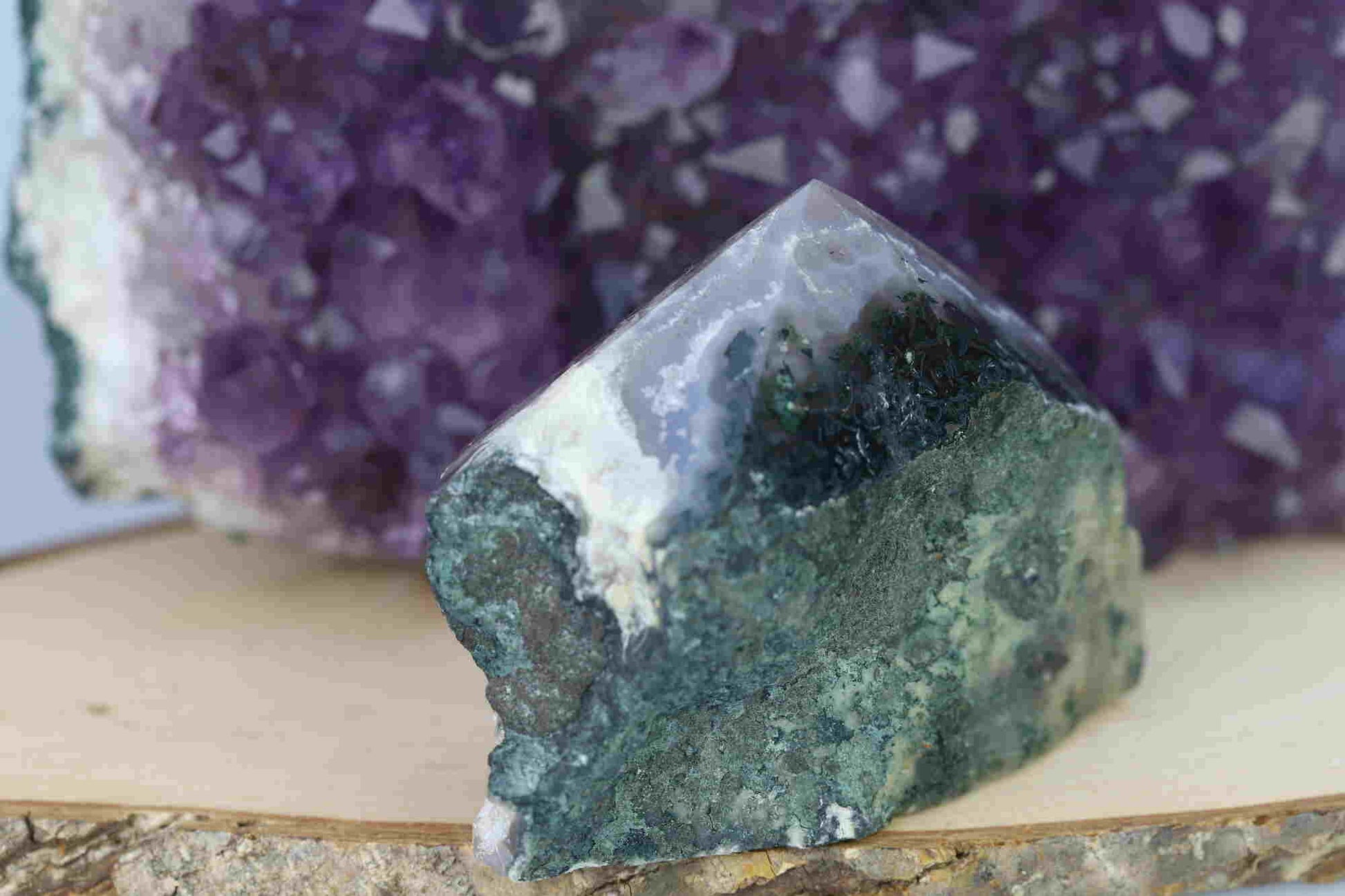 Kristallwerk präsentiert: Rohe Schätze Amethyst Spitze vor unscharfer Amethyststufe.