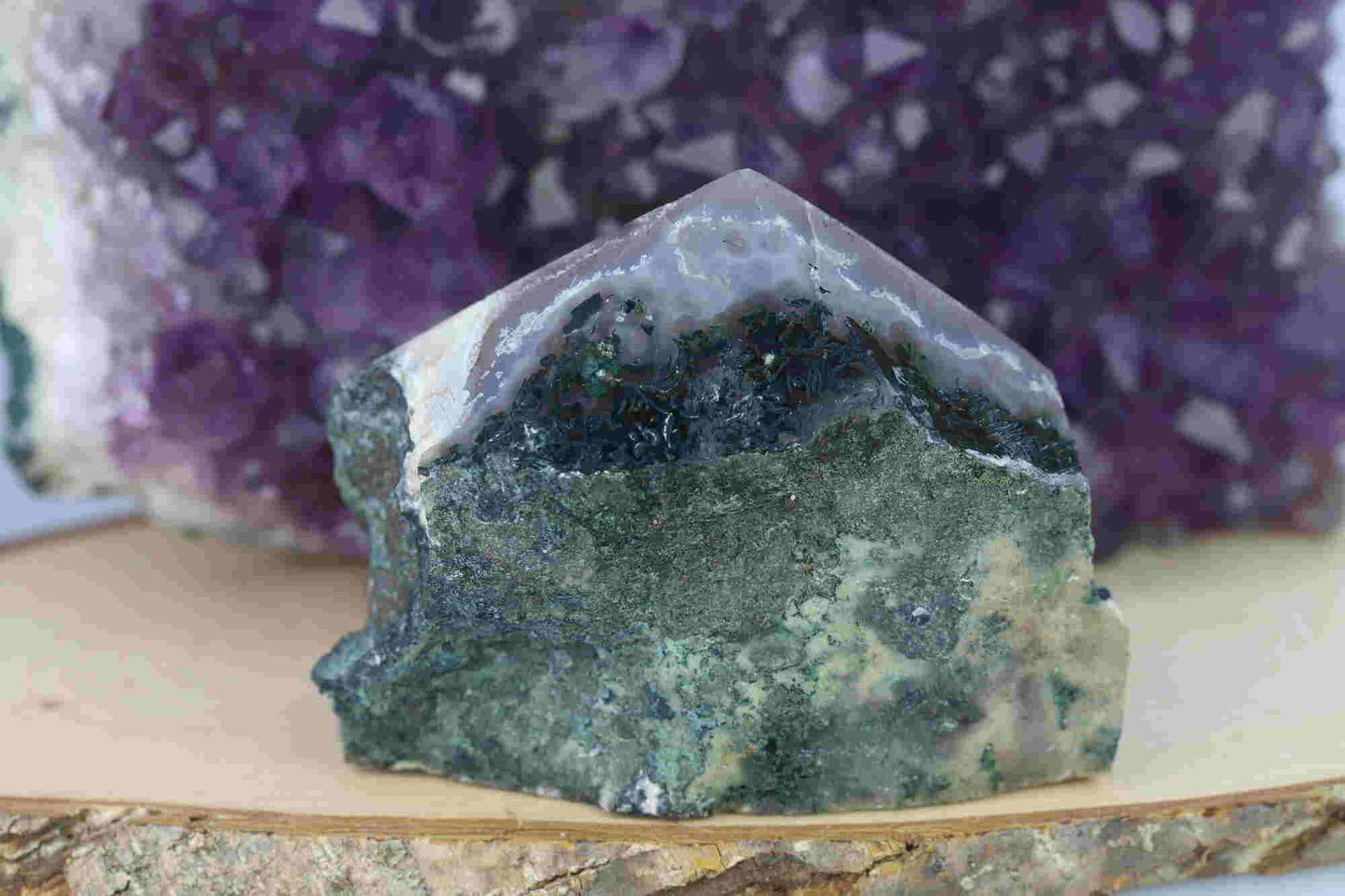 Kristallwerk präsentiert: Rohe Schätze Amethyst Spitze vor unscharfer Amethyststufe.