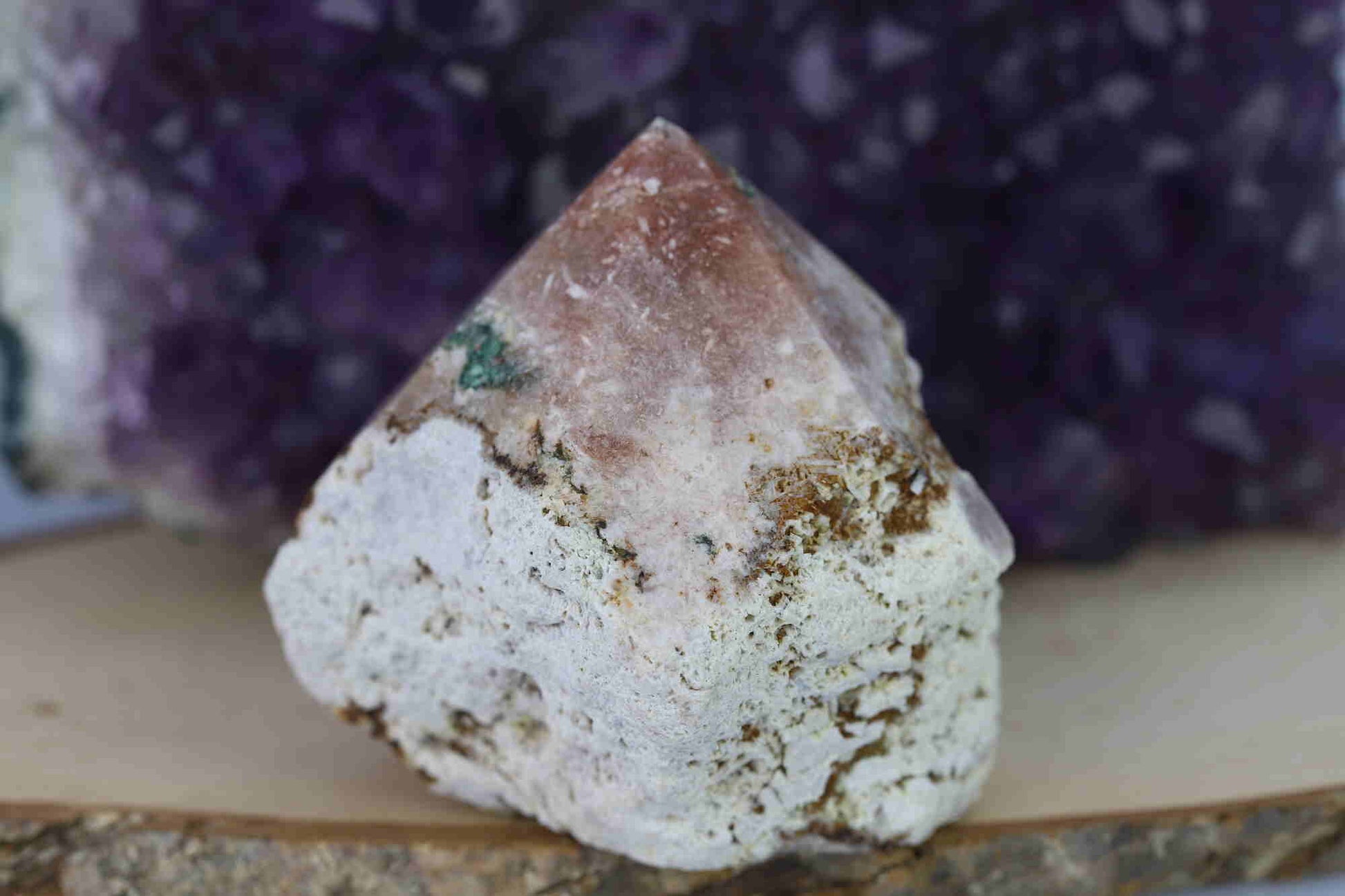 Kristallwerk präsentiert: Rohe Schätze Amethyst Spitze vor unscharfer Amethyststufe.