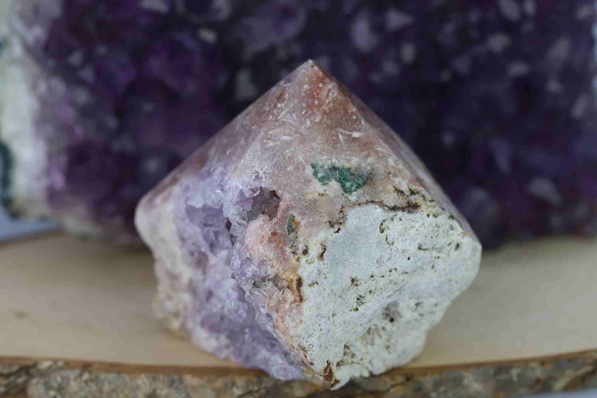 Kristallwerk präsentiert: Rohe Schätze Amethyst Spitze vor unscharfer Amethyststufe.