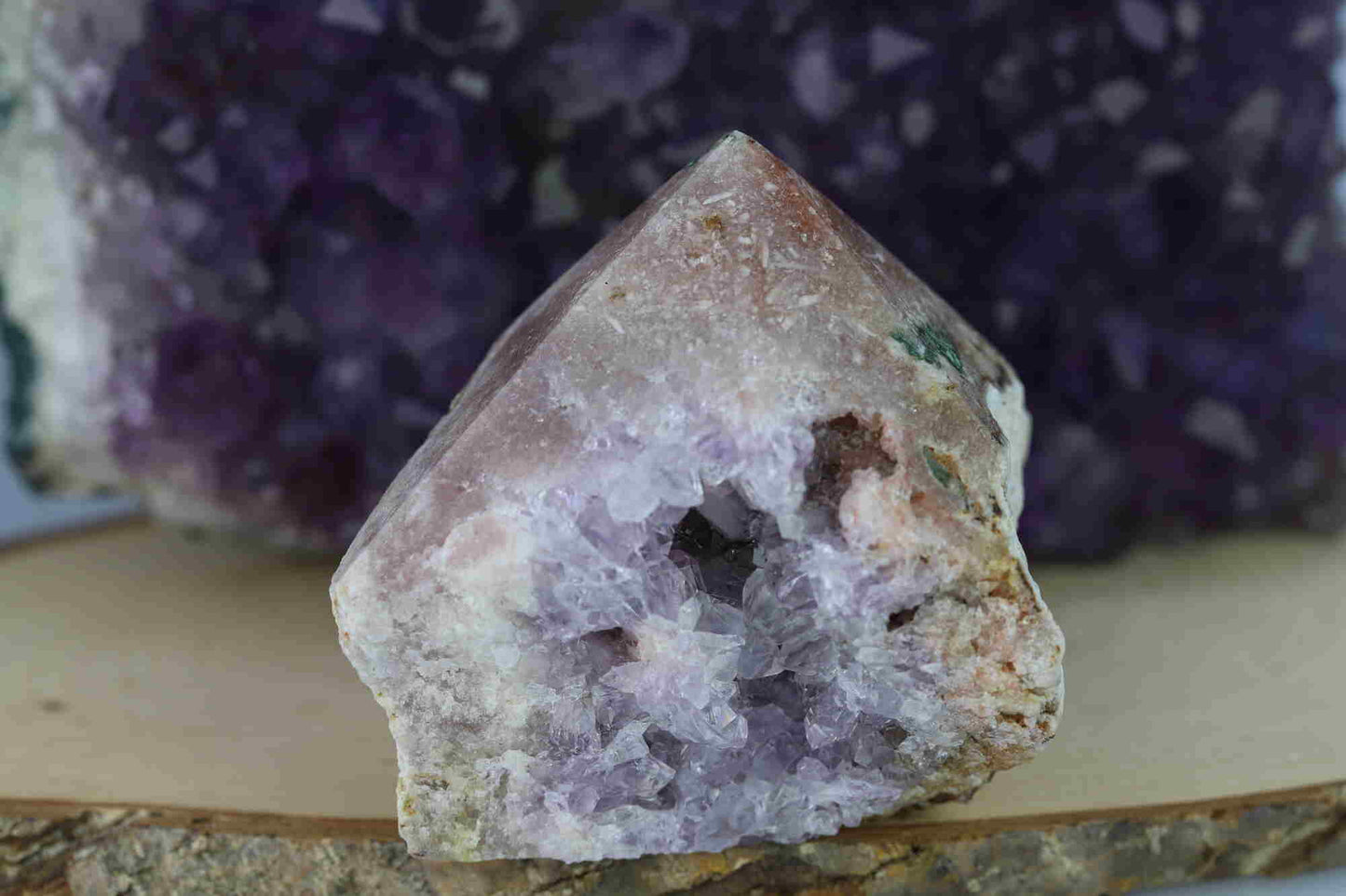 Kristallwerk präsentiert: Rohe Schätze Amethyst Spitze vor unscharfer Amethyststufe.