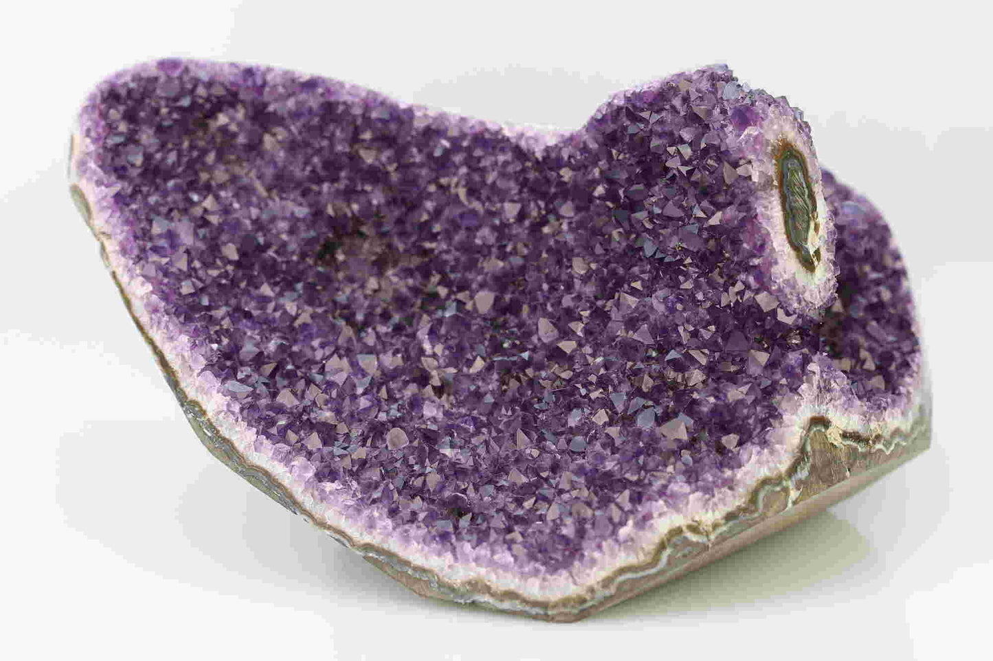 Kristallwerk präsentiert: Rohe Schätze Amethyst Herz Freeform Extra auf weiss glänzendem Untergrund.