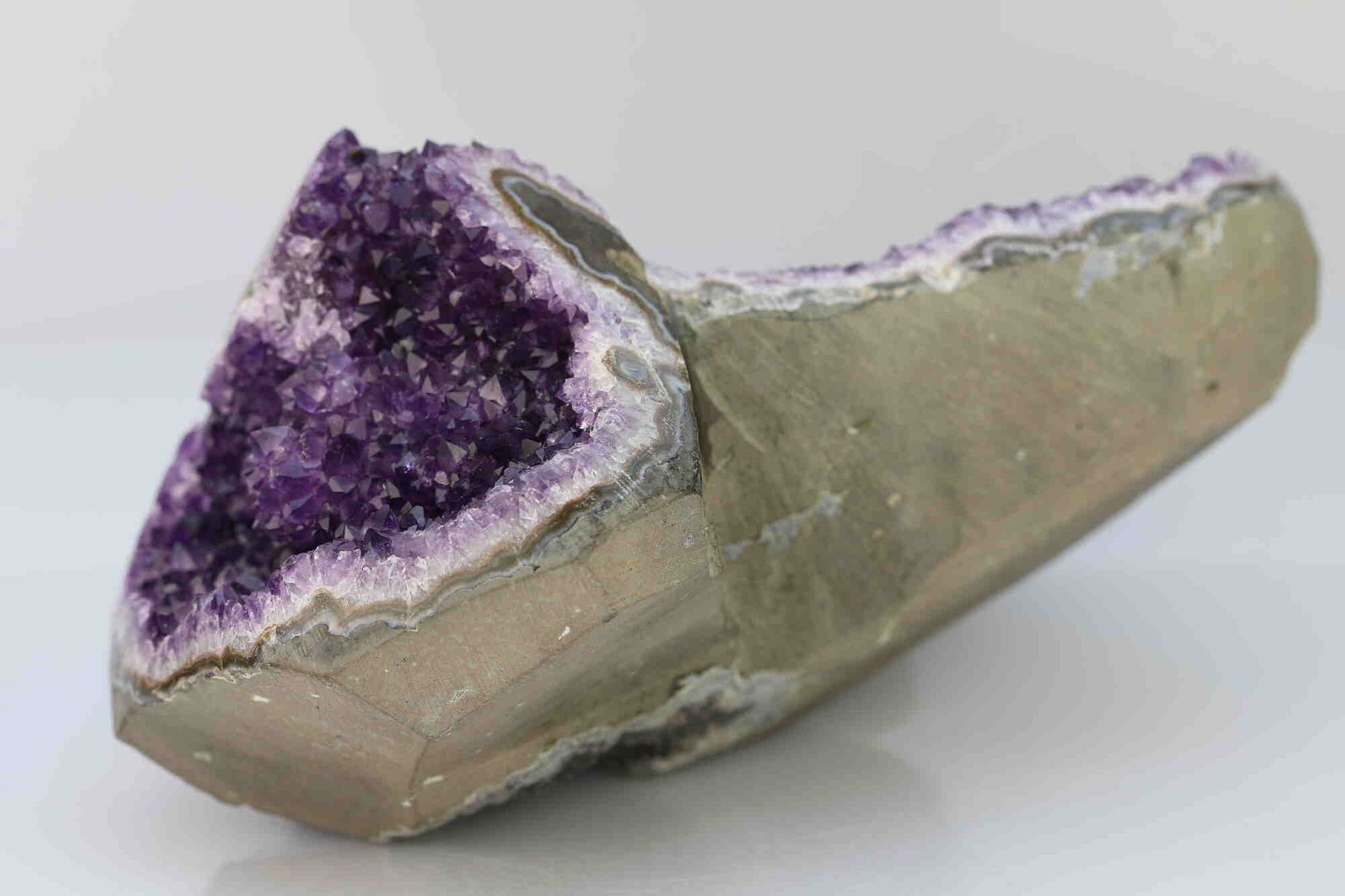 Kristallwerk präsentiert: Rohe Schätze Amethyst Herz Freeform Extra auf weiss glänzendem Untergrund.