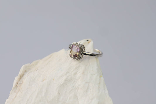 Kristallwerk präsentiert: Ring mit facettiertem Amethyst-Edelstein und umringt mit kleinen Bergkristallen aus Silber 925 auf weissem Stein.