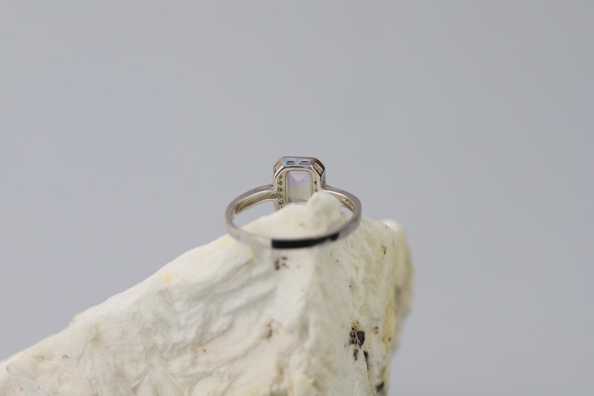 Kristallwerk präsentiert: Ring mit facettiertem Amethyst-Edelstein und umringt mit kleinen Bergkristallen aus Silber 925 auf weissem Stein.